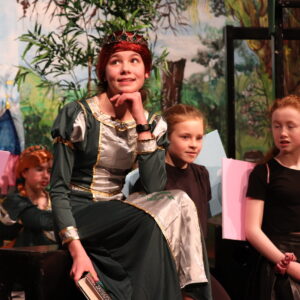 A photo of Princess Fiona with her chorus on the stage.