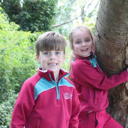 Two children from Senior Infants holding on to a tree, having fun