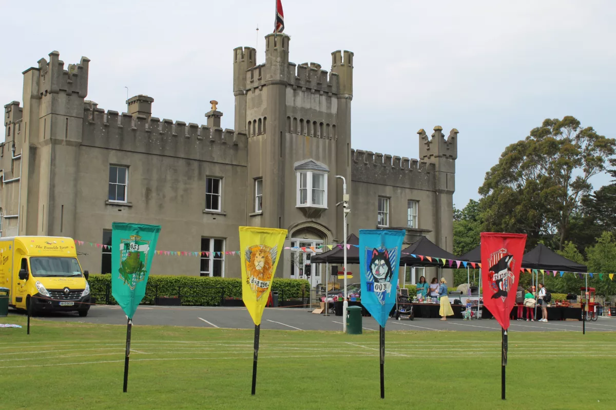 A photo of the Castle Building with the 4 House Flags on the pitch in front