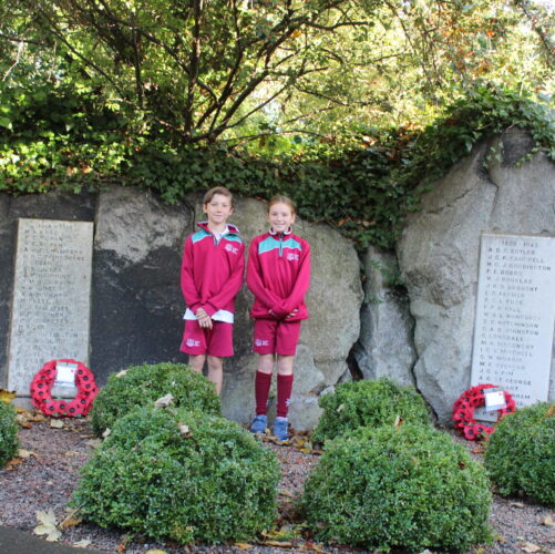 An image of 2 Castle Park pupils standing by the wreaths in our Remembrance Garden